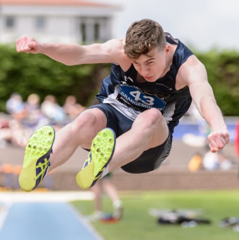 Stephen Mackenzie competing in long jump.